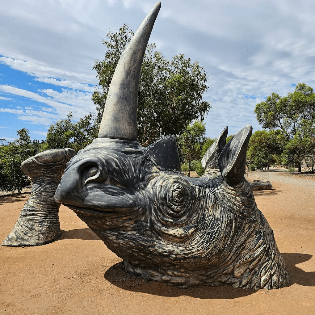 A rhinoceros head sculpture in a desert setting during a school excursion