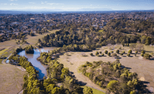 An aerial view of a river flowing through Manningham's lush green fields