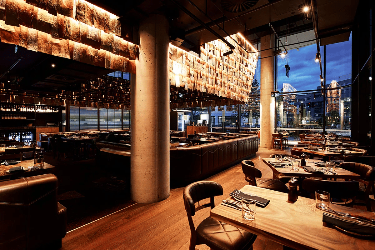 Dimly lit restaurant with wooden tables and chairs in Canberra