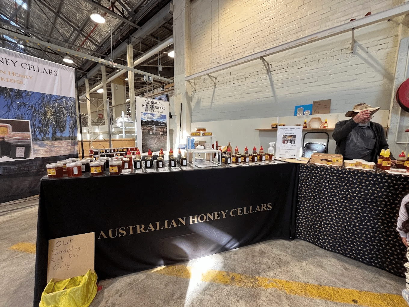 Man next to table with honey bottles in Canberra food market