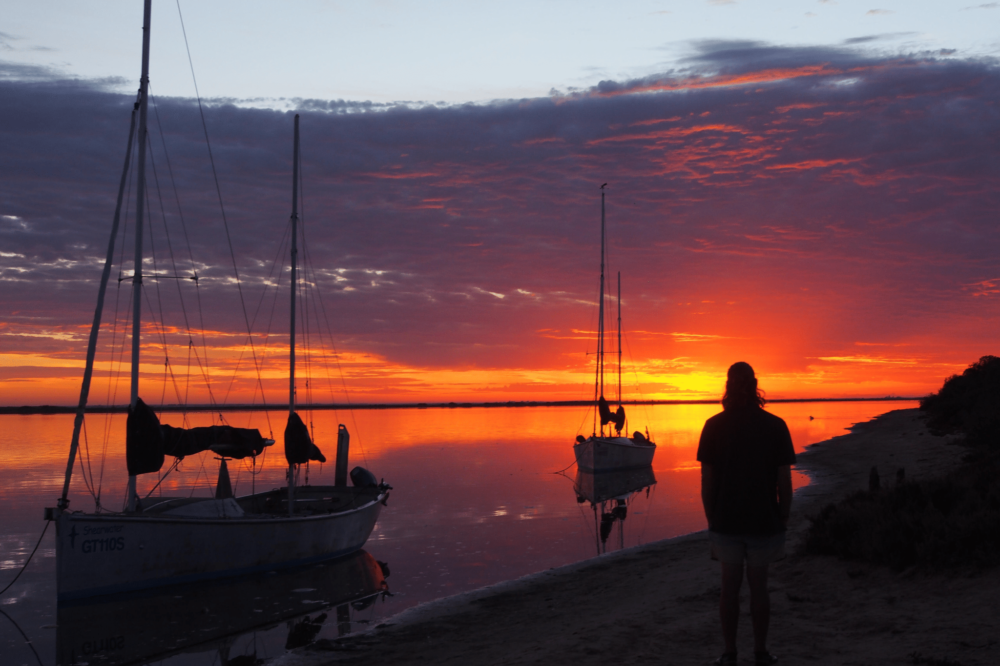 Person on beach next to boat in Adelaide