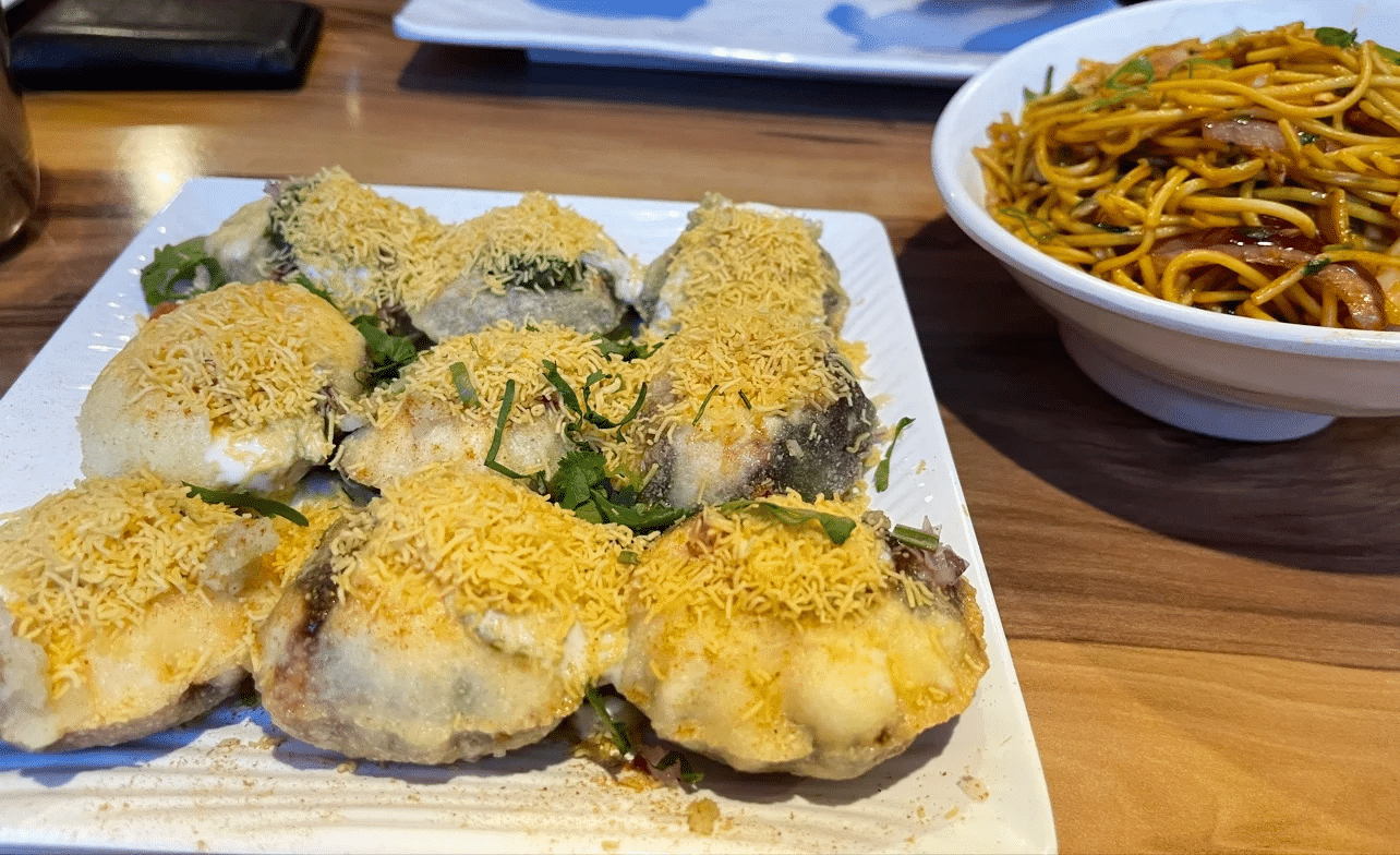 White plate with food next to a bowl of noodles on Gold Coast food tour