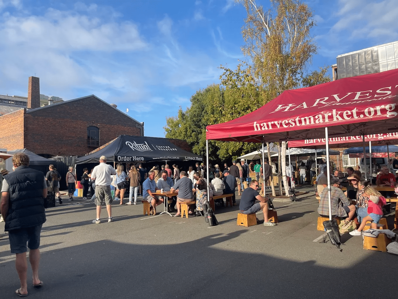 A group gathering under a red awning at a Launceston event