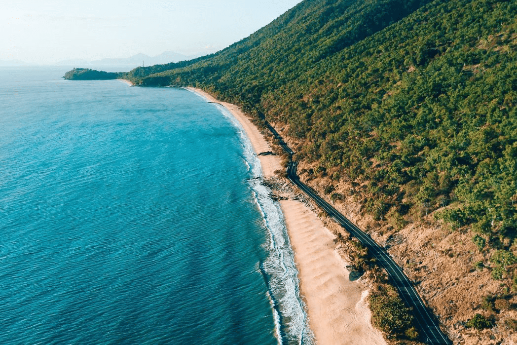 An aerial view of a Queensland beach with a train on tracks