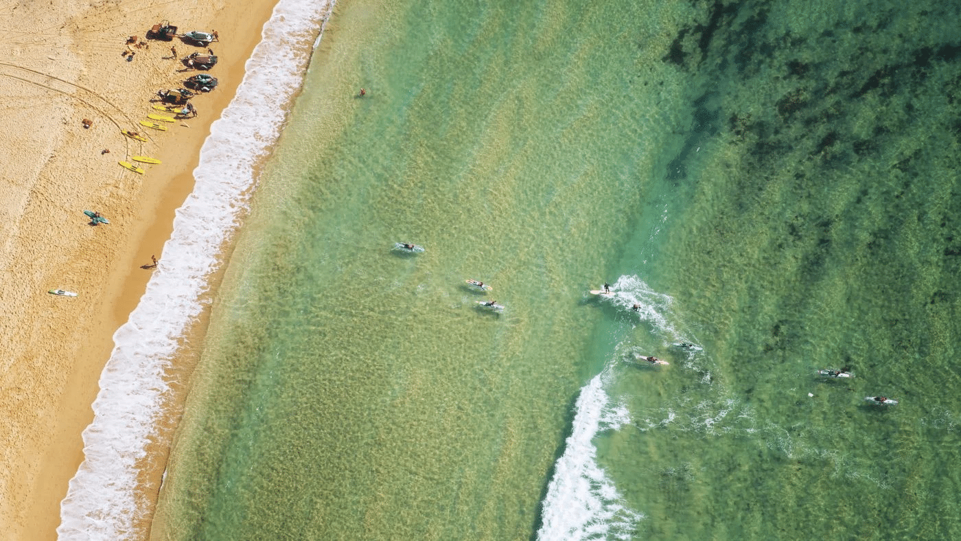 An aerial view of Central Coast beach with people swimming