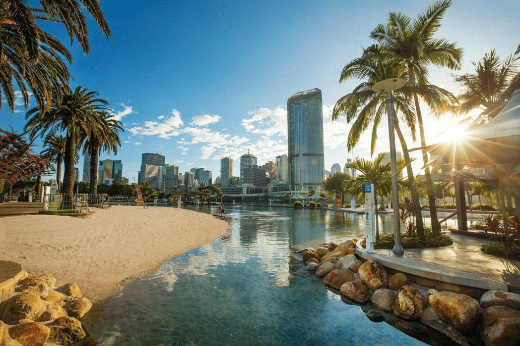 Beach with palm trees and Brisbane city skyline