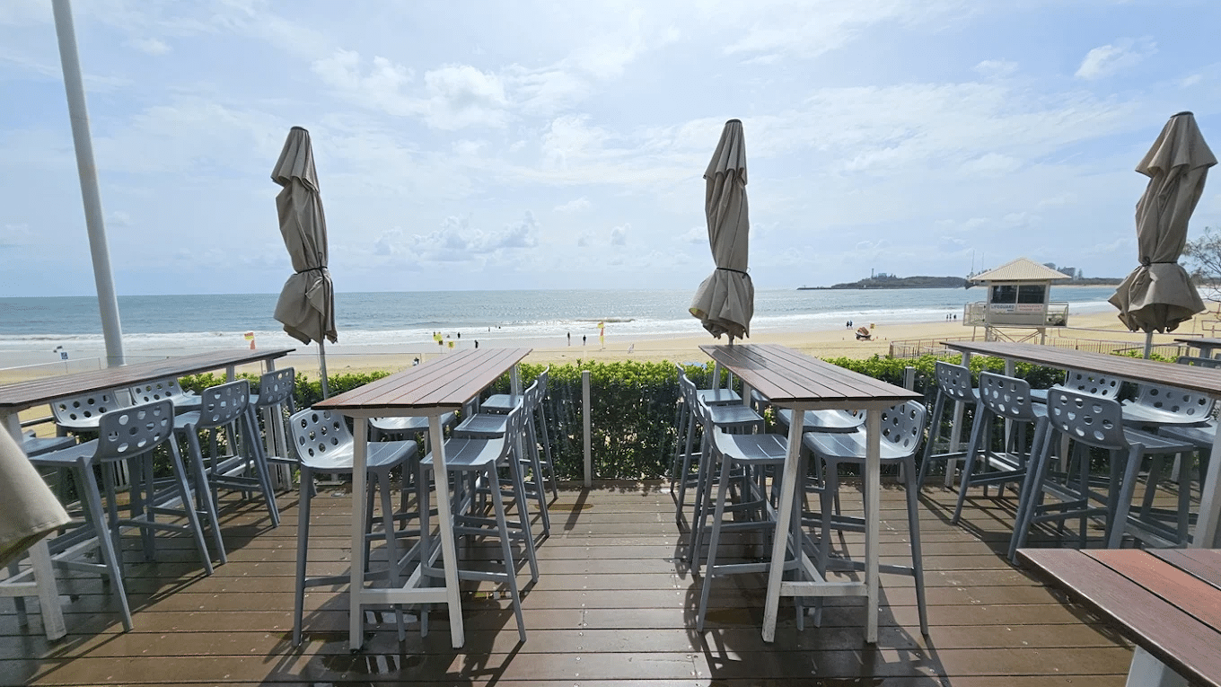 beachfront dining area with tables and chairs on wooden deck