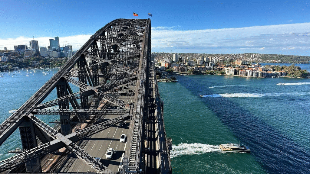 Boat crossing Sydney Harbour Bridge over blue water