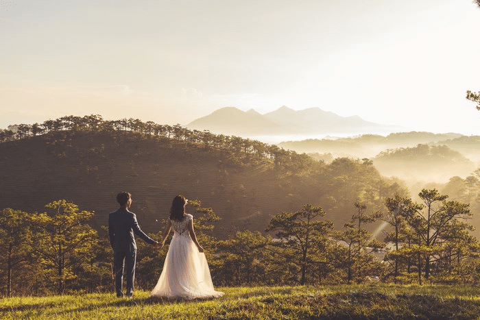 Bride and groom holding hands on hilltop