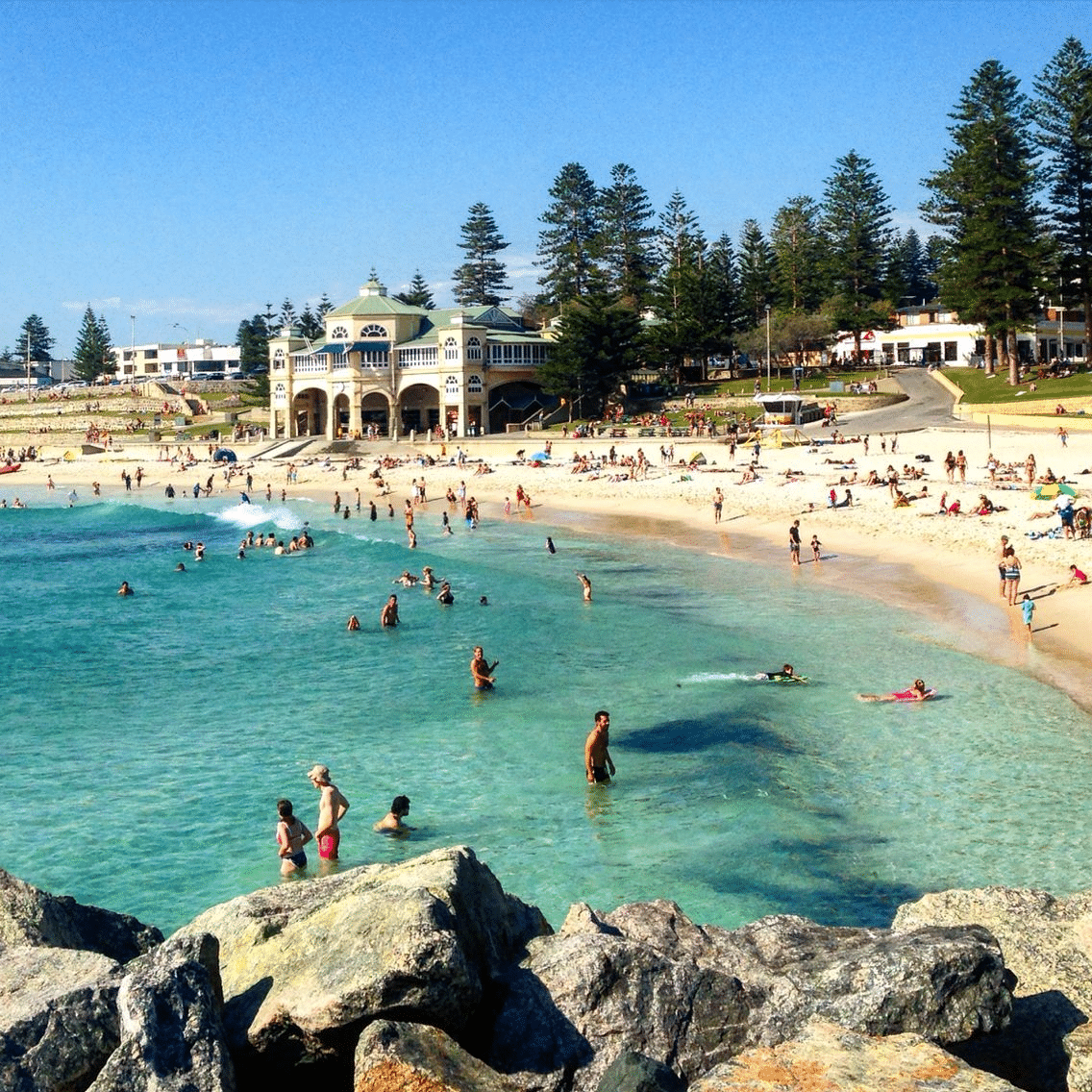 Crowded beach with families enjoying water activities in Perth