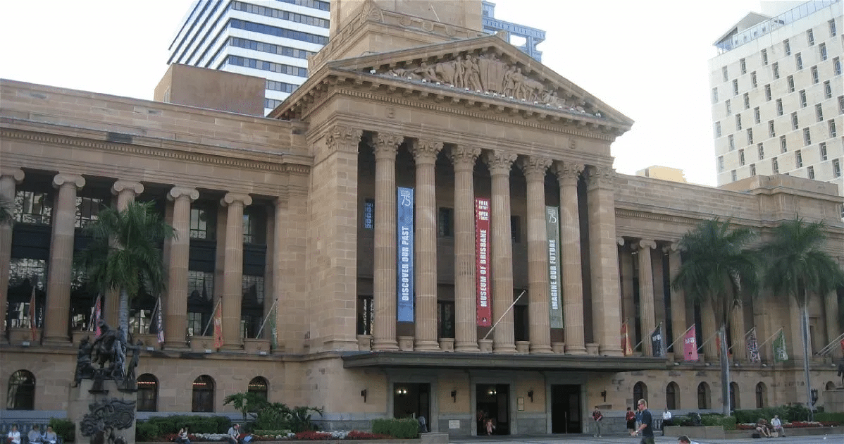 Front view of a historical building with columns and flags at Roma Street Parkland in Brisbane
