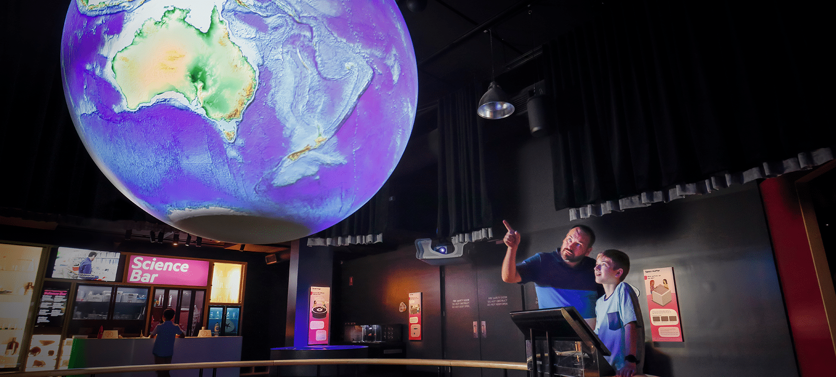 Man and woman standing in front of large globe at Queensland Museum Brisbane