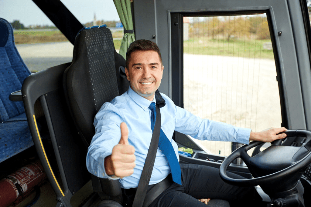 Man sitting in bus driver's seat giving thumbs up