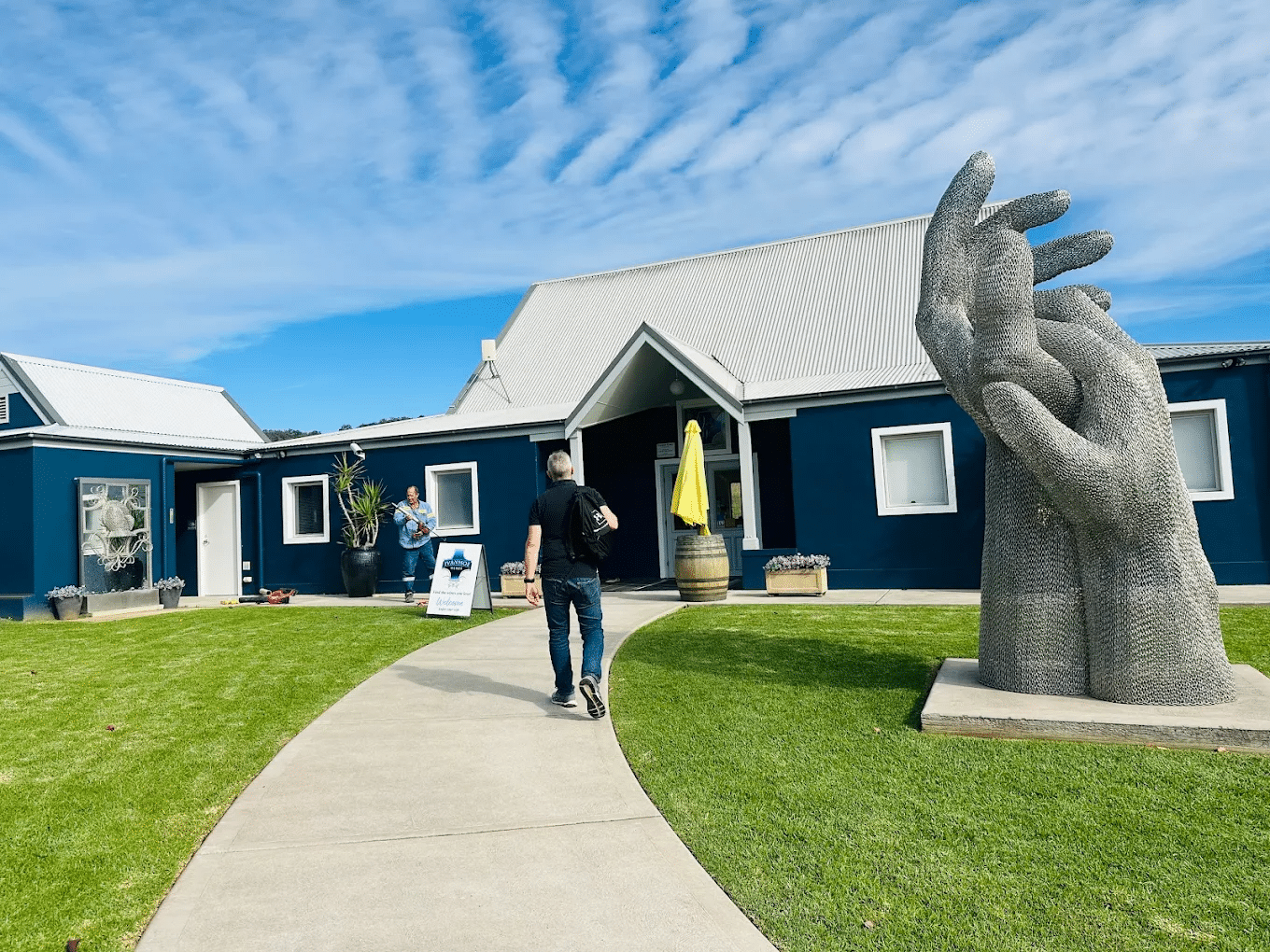 Man walking on sidewalk near hand statue