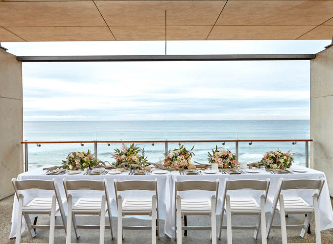 Ocean-view long table with white chairs for a Christmas party in Sydney
