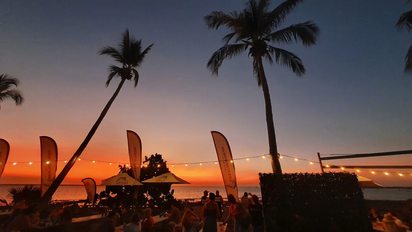 People enjoying a beach view near palm trees in Darwin