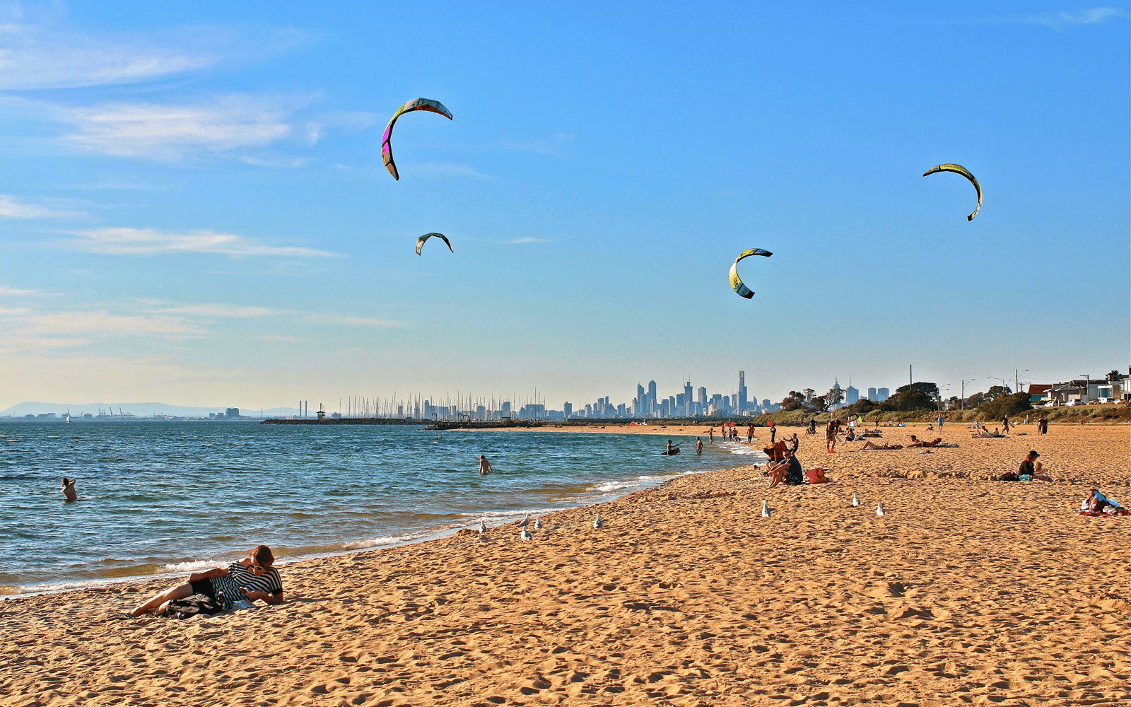 People flying kites on a sandy beach in Bayside Melbourne