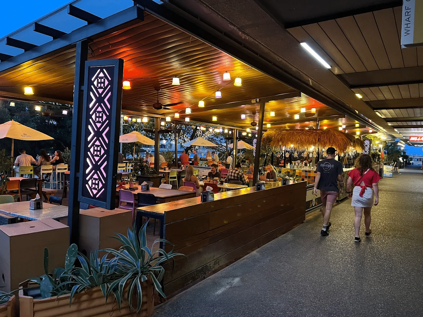 People walking on a walkway near a restaurant during a food tour in Darwin