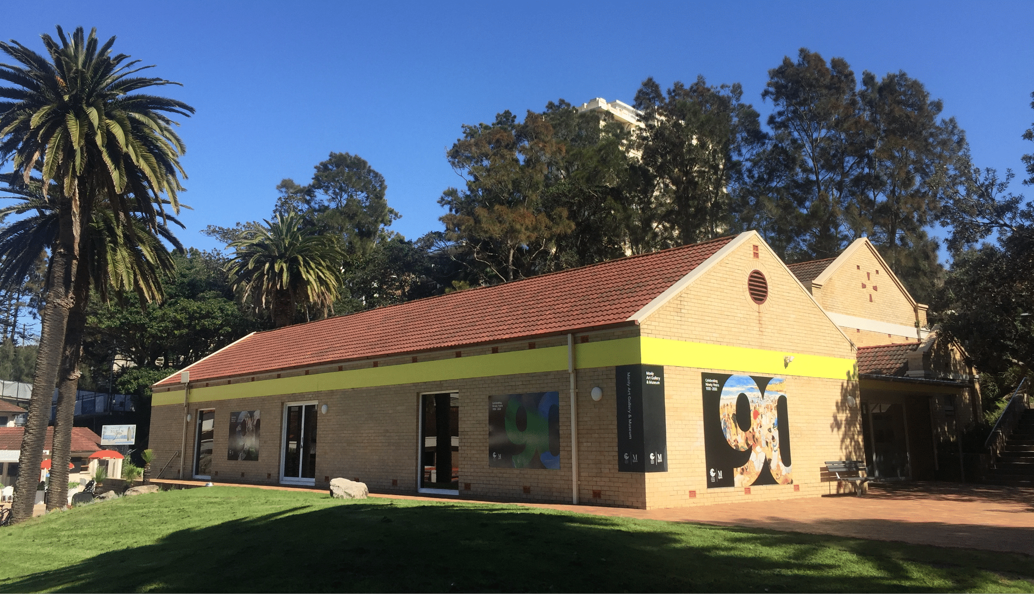 Small building with red roof and palm tree in Manly