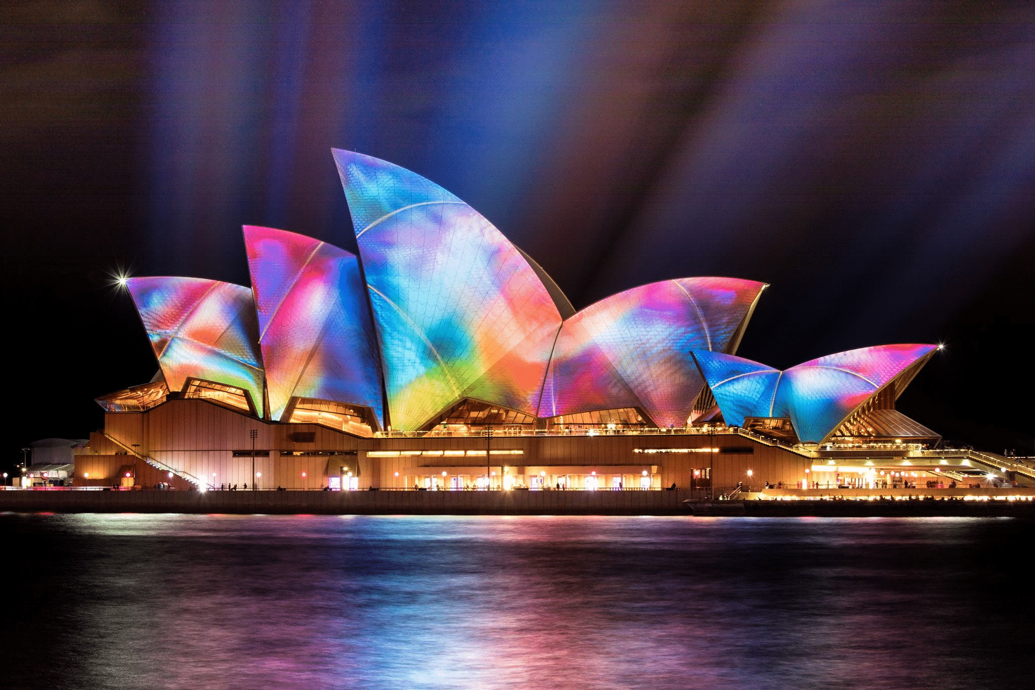 Sydney opera house illuminated with colorful lights at night