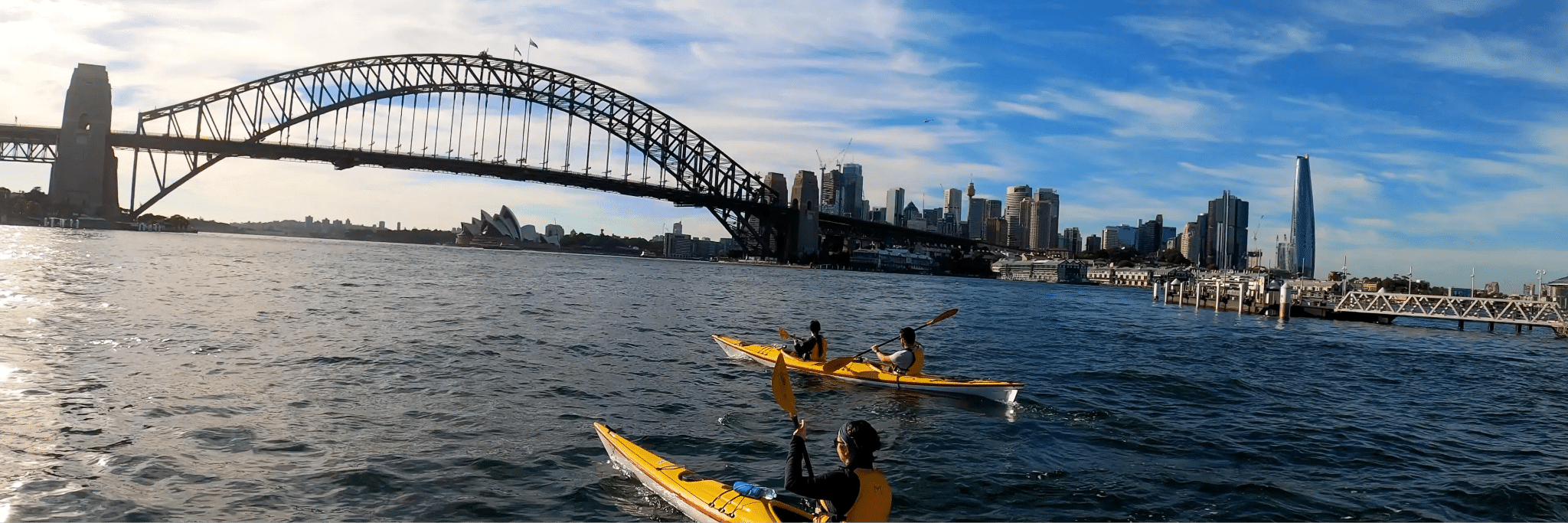 Two kayakers under Sydney bridge during team building adventure