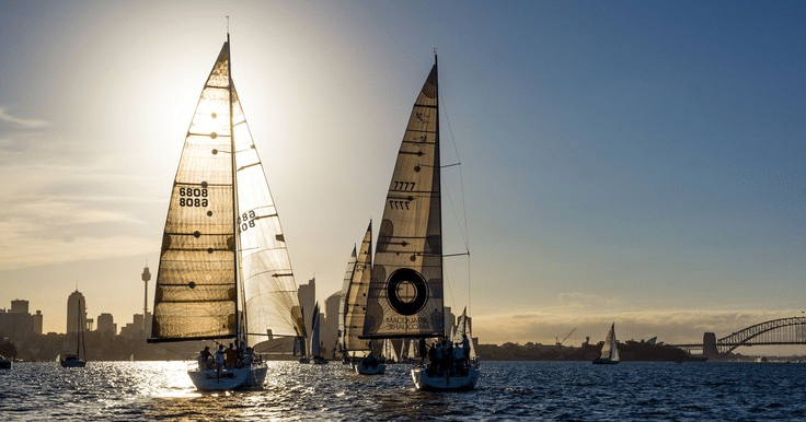 Two sailboats on water near Sydney bridge